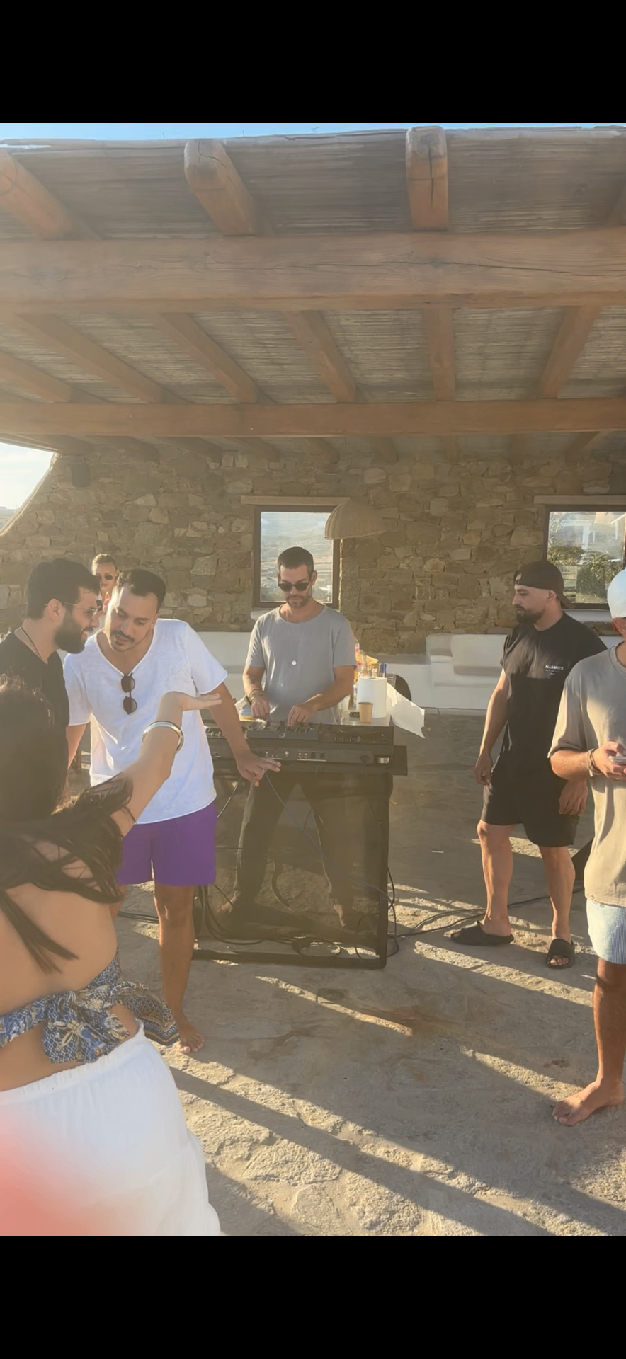Golden hour DJ set with guests gathered around the booth